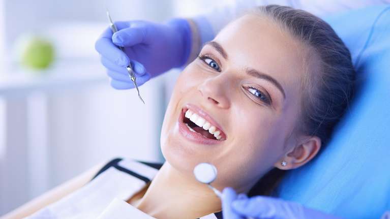 woman smiling in dentist exam chair | dentist chelsea